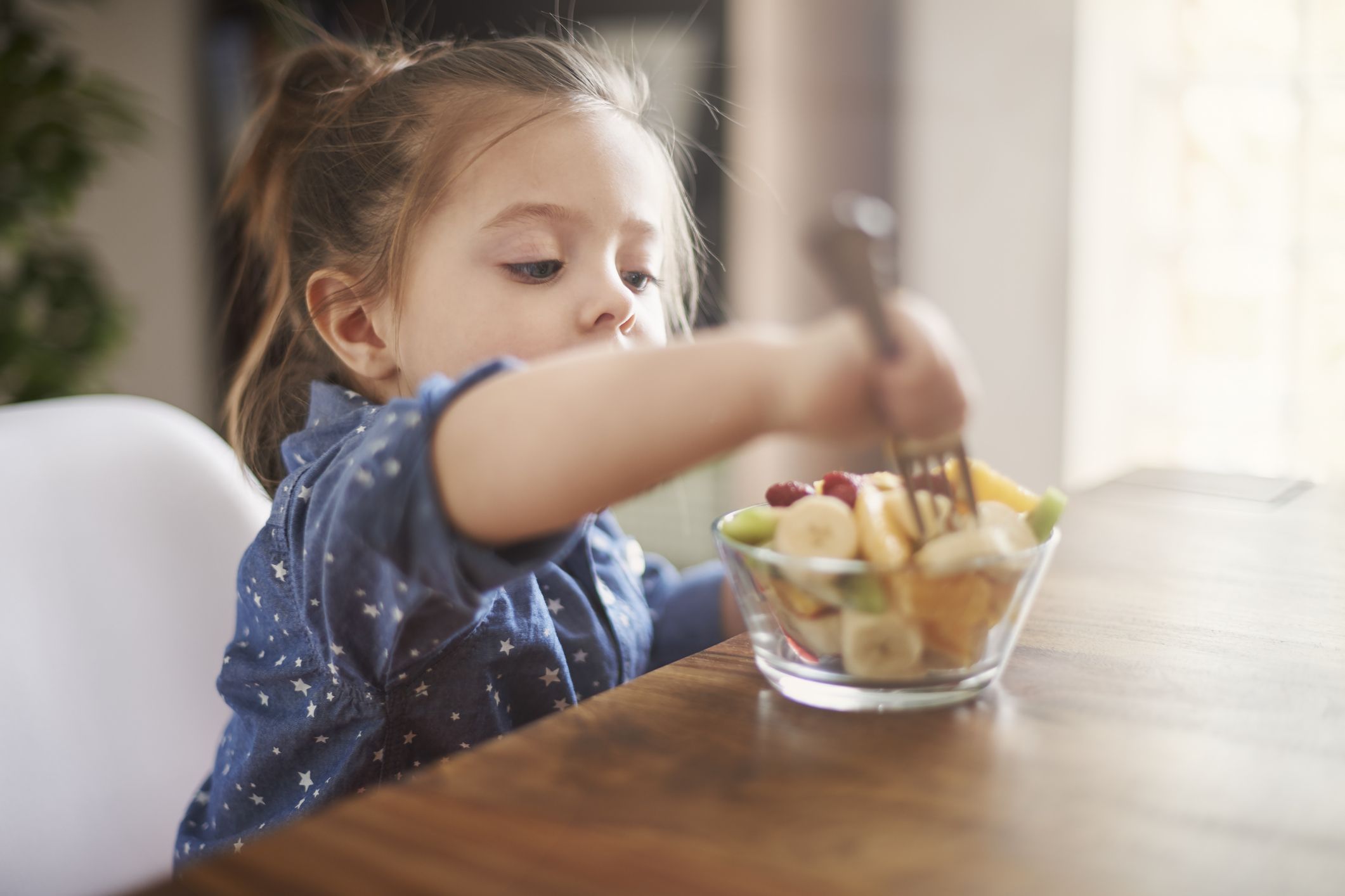 Petite fille ayant une salade de fruits.